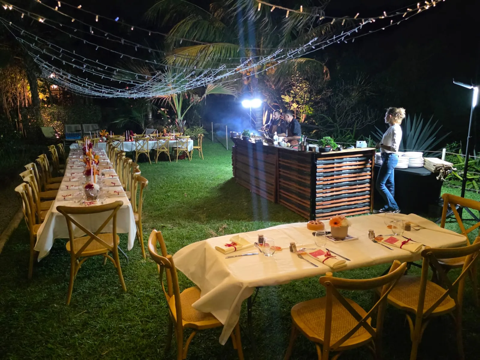 Tables de mariage dressées dans un jardin sous des guirlandes lumineuses